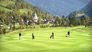 Un campo de golf con una iglesia y casas al fondo.