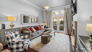Een woonkamer met een bank, fauteuil, salontafel en televisie.