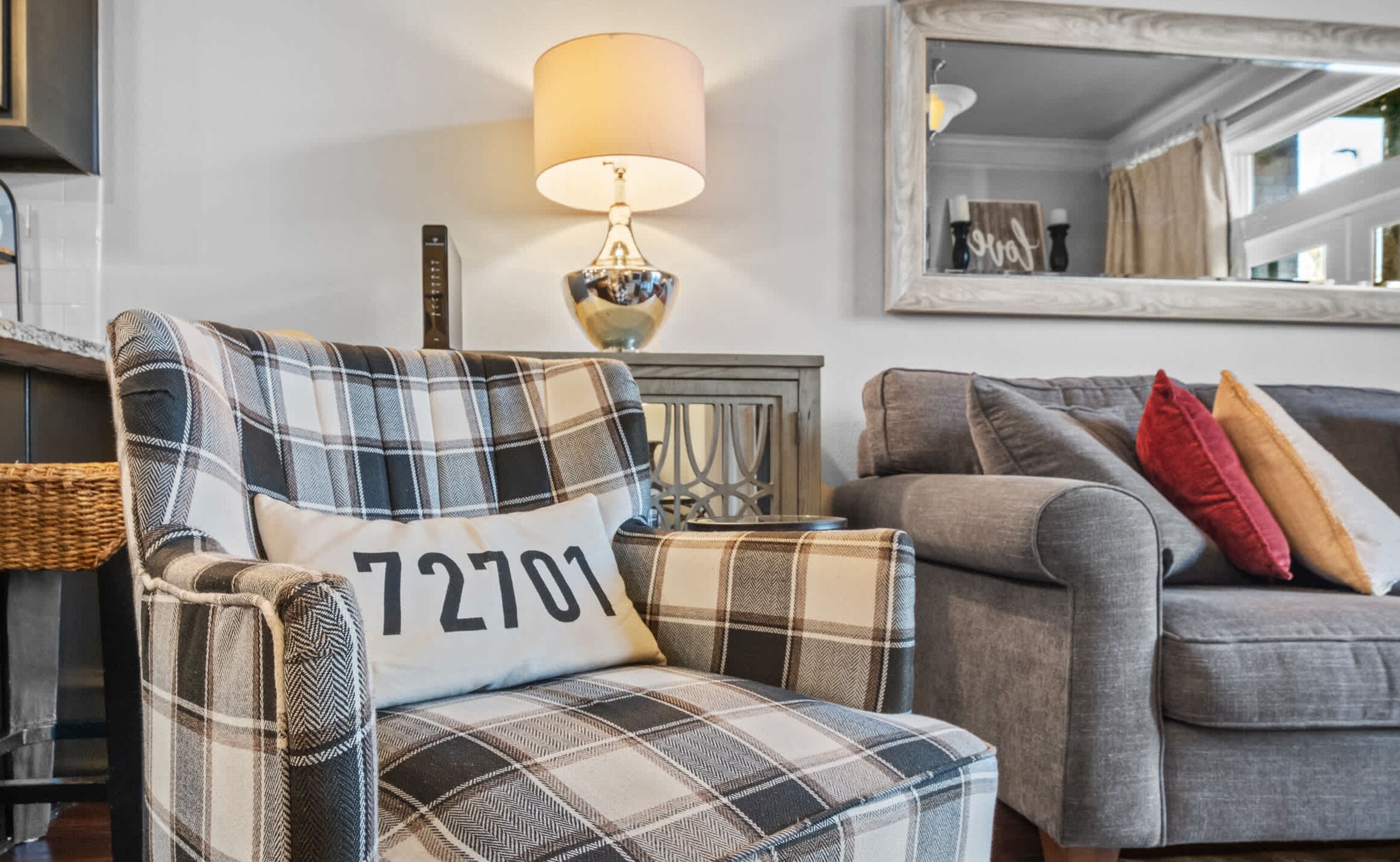 A living room with a plaid armchair, a sofa, and a lamp.