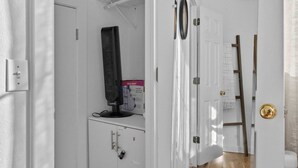 A narrow hallway with a white door, a mirror, and a ceiling fan.