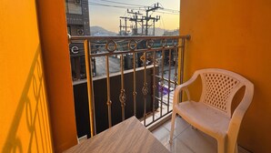 A balcony with a metal railing, a white plastic chair, and a table. - Stay At Bedroom (Patong)