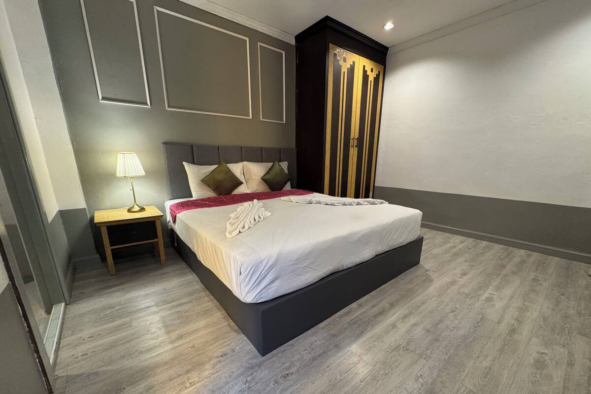 A modern bedroom with a bed, bedside table, lamp, and wardrobe.
