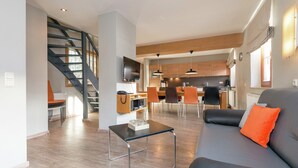 A modern living room with a sofa, a coffee table, and a staircase leading to a kitchen area. - Chalet in Dienten on Hochkönig Ski Slopes (Dienten)