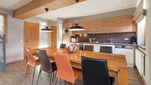 A modern kitchen with wooden cabinets, a central island with chairs, and pendant lighting. - Chalet in Dienten on Hochkönig Ski Slopes (Dienten)