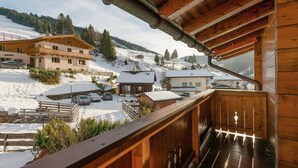 A wooden balcony with a view of a snowy village, including buildings and a car parked in front. - Chalet in Dienten on Hochkönig Ski Slopes (Dienten)