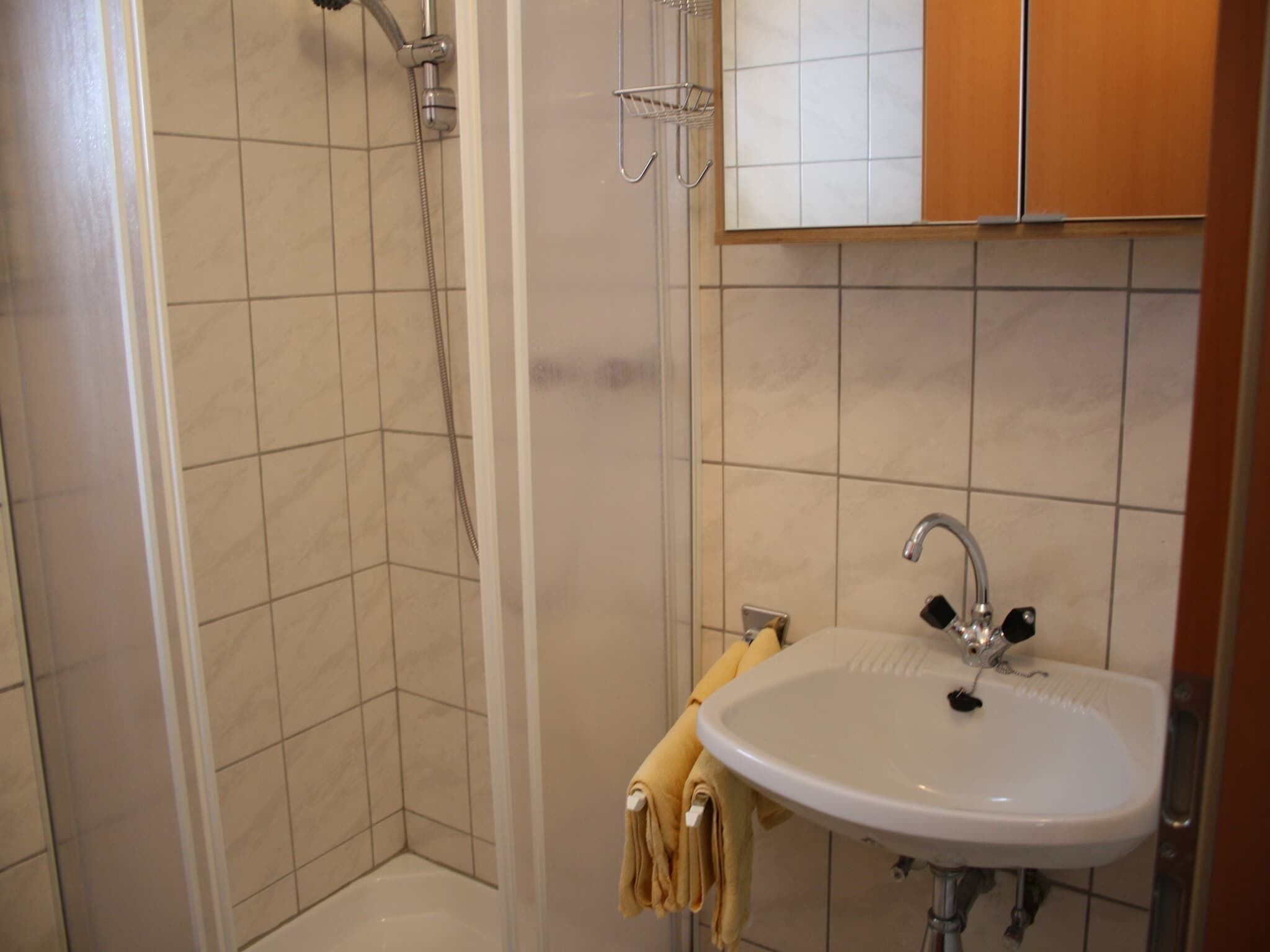 A bathroom with a shower, a sink, and a towel rack.