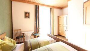 A room with two beds, a wooden ceiling, a small table with a chair, and a wardrobe. - Chalet in Austria near Ski Slopes (Mittersill)