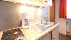 A compact kitchen with a coffee maker, a sink, and a stove. - Chalet in Austria near Ski Slopes (Mittersill)