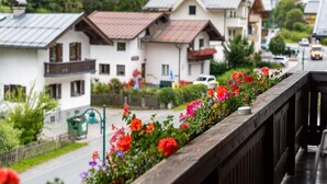 Ein Balkon mit Holzbalkon, der auf eine Straße mit Häusern und Blumen blickt.