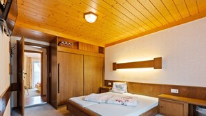 Ein Schlafzimmer mit einem hölzernen Bett, einem Nachttisch, einem Kleiderschrank und einer Deckenleuchte.