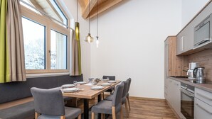 A modern kitchen with a wooden dining table, grey chairs, and a built-in oven. - Chalet in Saalbach near Ski Lift (Saalbach-Hinterglemm)