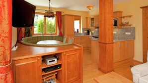 Una cocina compacta con armarios de madera, una mesa de comedor y un televisor integrado.
