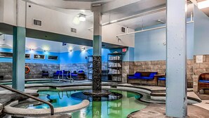 A spa area with multiple hot tubs, seating areas, and a central column. - Spacious Resort Condo | Near Banff (Canmore)