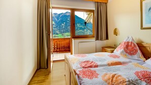 A bedroom with a bed, a nightstand, a window with a view of mountains, and a wooden ceiling. - Apartment in Fügenberg near Ski Lift (Fügenberg)