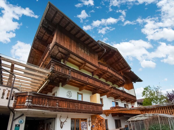 A multi-story building with wooden balconies and a clock on the facade. - Apartment in Fügenberg near Ski Lift (Fügenberg)