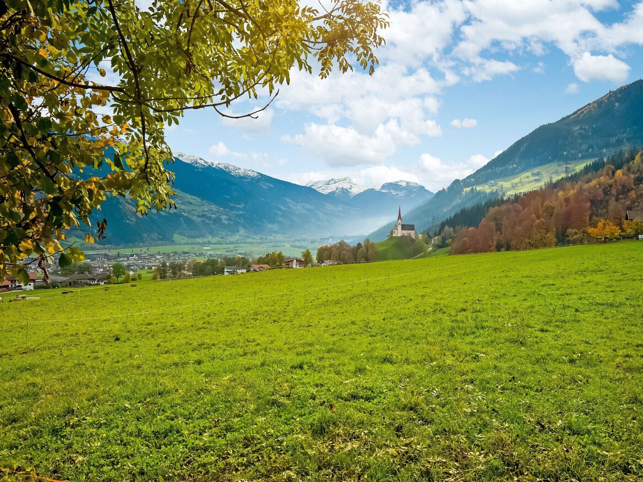 A green field with a church and mountains in the background.