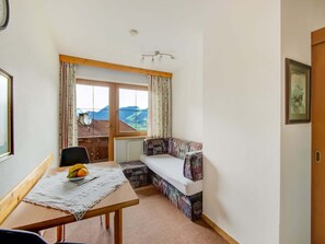Una habitación con una mesa de madera, un banco y vistas a las montañas a través de una ventana.