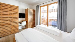 A modern bedroom with a bed, a TV, a desk, and a wardrobe. - Apartment in Gerlos near Ski Lift (Gerlos)