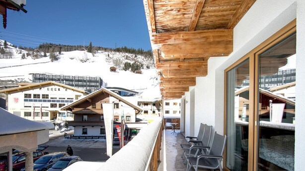 A balcony with a view of a snowy mountain and buildings in the background. - Apartment in Gerlos near Ski Lift (Gerlos)