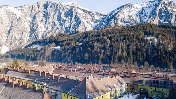 A town with traditional architecture, a central street, and snow-covered mountains in the background. - Apartment in Styria with bubble bath (No Deposit) (Eisenerz)