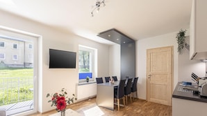 A modern kitchen with a dining area, a TV mounted on the wall, and a view of the outside. - Apartment in Styria with bubble bath (No Deposit) (Eisenerz)