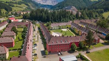 Ein Wohngebiet mit roten und gelben Gebäuden, einem zentralen Innenhof und einer Bergkulisse im Hintergrund.