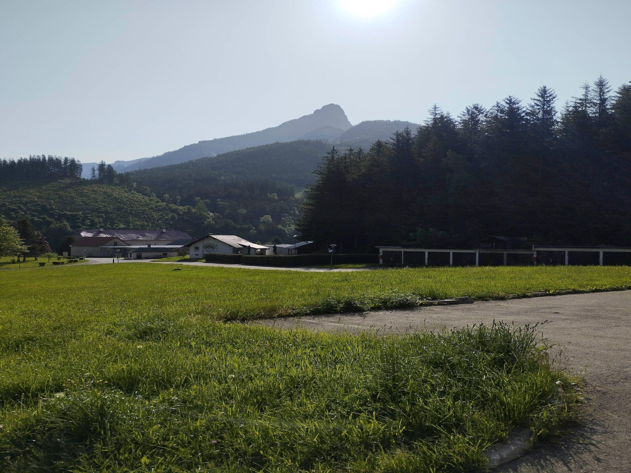 A rural landscape with a clear sky, a mountain in the background, and a field in the foreground.