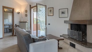 Una sala de estar con chimenea, sofá, comedor y vistas al exterior.