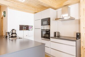 A modern kitchen with stainless steel appliances, a large island, and wooden ceiling beams. - Premium apartment with infrared sauna (Kreischberg Murau)