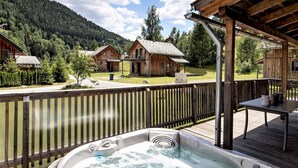 Uma banheira de hidromassagem em um deck de madeira com vista para cabanas e montanhas.
