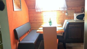 Ein kleiner Essbereich mit einem Holztisch, einer Bank und einer Mikrowelle.