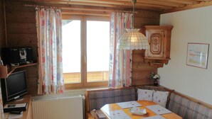 A cozy cabin interior with a wooden dining table, cushioned benches, a television, and a radiator. - Apartment in Nassfeld (Nassfeld)