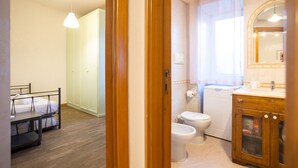 A room with a bed, a wooden cabinet with a mirror, a toilet, and a shower area. - La Casa di Daeny in Naples (Naples)