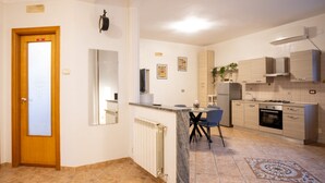 A modern kitchen with a marble countertop, a dining area with a table and chairs, and a built-in oven. - La Casa di Daeny in Naples (Naples)