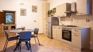 A modern kitchen with a dining area, featuring a round table, chairs, and a refrigerator. - La Casa di Daeny in Naples (Naples)