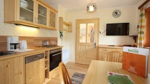 Cocina con armarios de madera, lavavajillas, estufa y una mesa de comedor con un folleto de Belvilla.