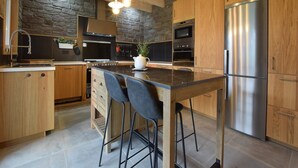 Une cuisine moderne avec des meubles en bois, un réfrigérateur en acier inoxydable et un îlot central doté de tabourets de bar.