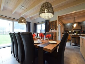 A dining area with a wooden table, black chairs, and a large window.