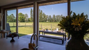 A kitchen with a large window, a sink, and a dining area with a bench and table. - Beautiful Holiday Home with Terrace, Garden (Diksmuide)