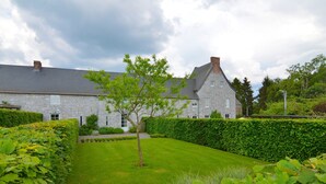 A stone building with a well-maintained lawn and hedges. - Elegant Estate Stay, Maredsous (Maredsous)