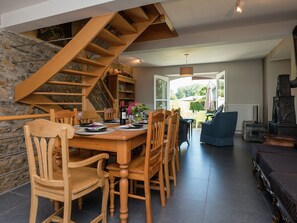 Ein Essbereich mit einer Holztreppe, einem Tisch für sechs Personen und einem blauen Sofa im Hintergrund.
