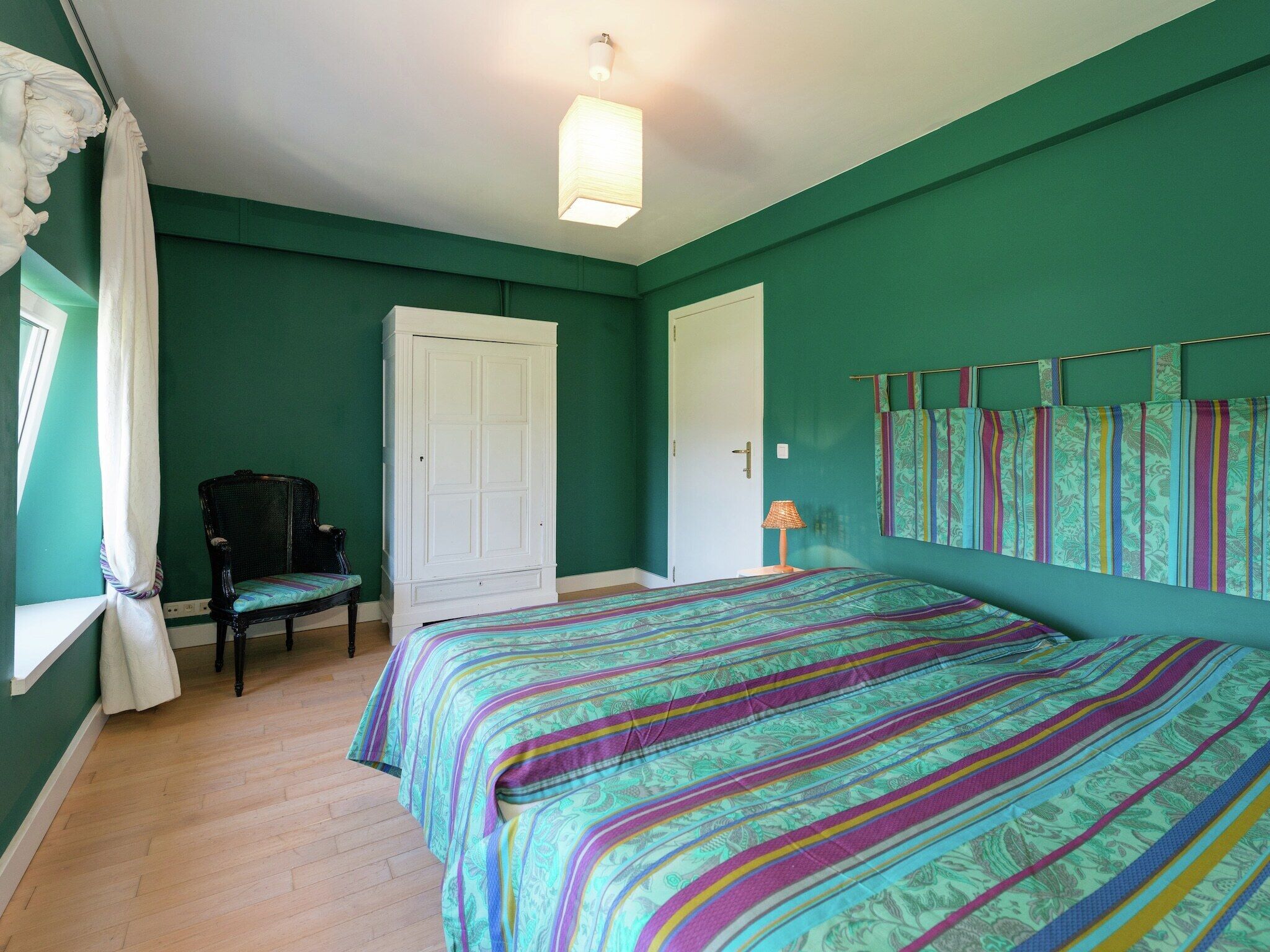 Une chambre à coucher avec un lit, une chaise, une armoire et une porte.