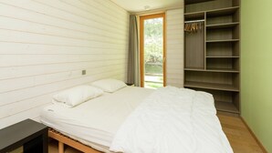 A bedroom with a bed, a bedside table, a wardrobe, and a door leading to an outdoor area.