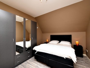 Relax in this cozy loft-style bedroom with a large wardrobe and comfortable bed.