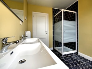 Features a dual sink vanity and glass shower enclosure.
