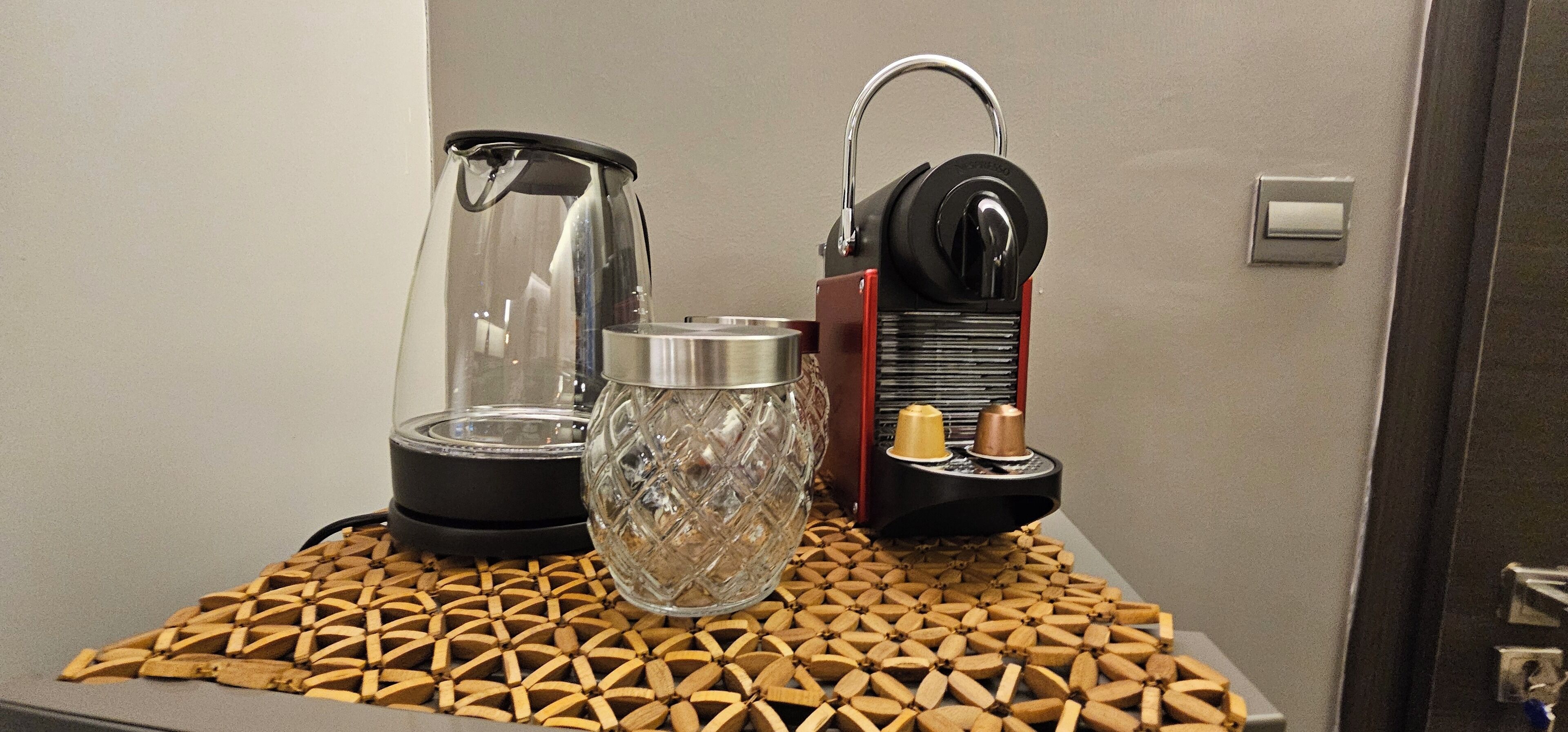 Een koffiezetapparaat met een glazen kan en een metalen reservoir op een geweven onderzetter.