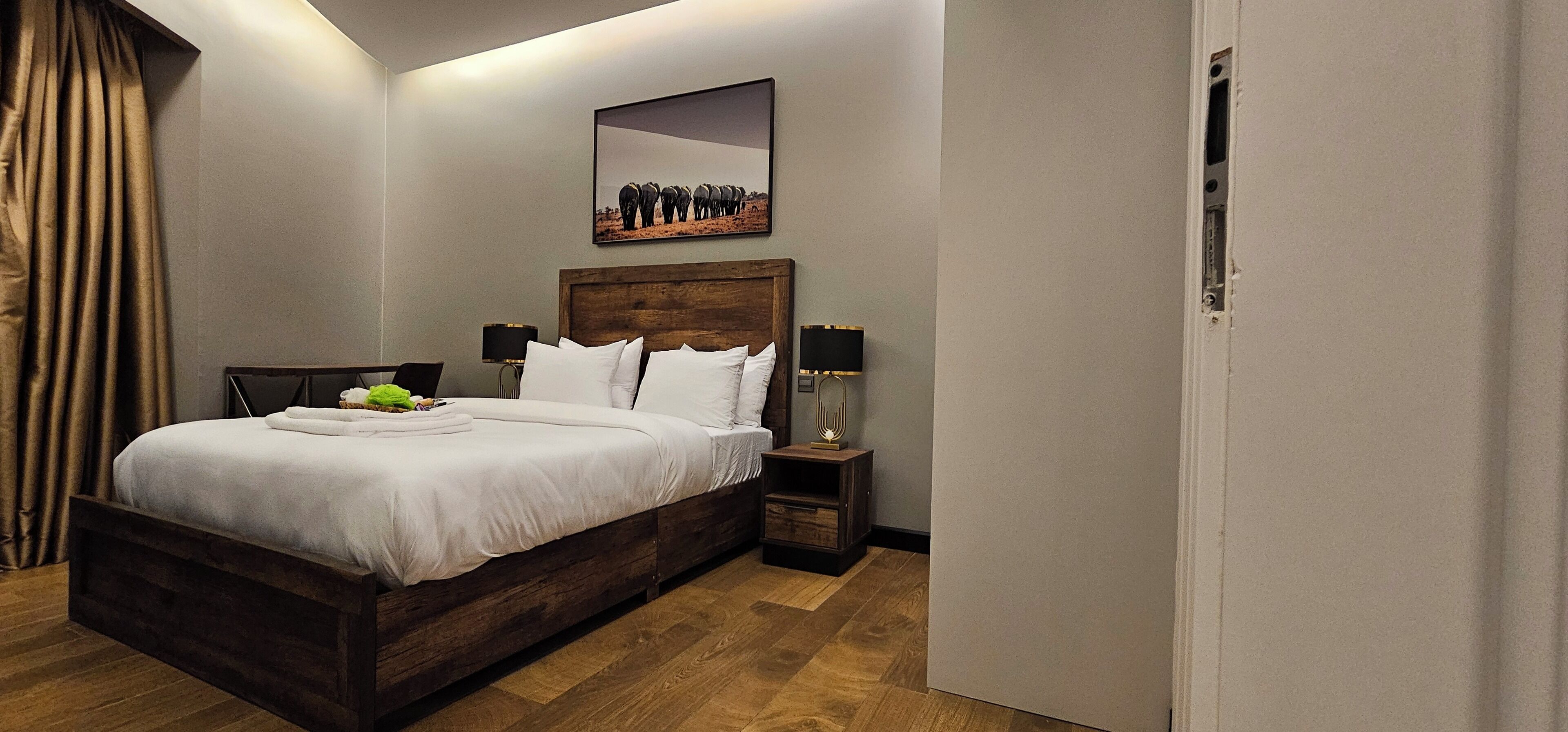 A neatly made bed with white linens, a bedside table with a lamp, and a framed picture on the wall.