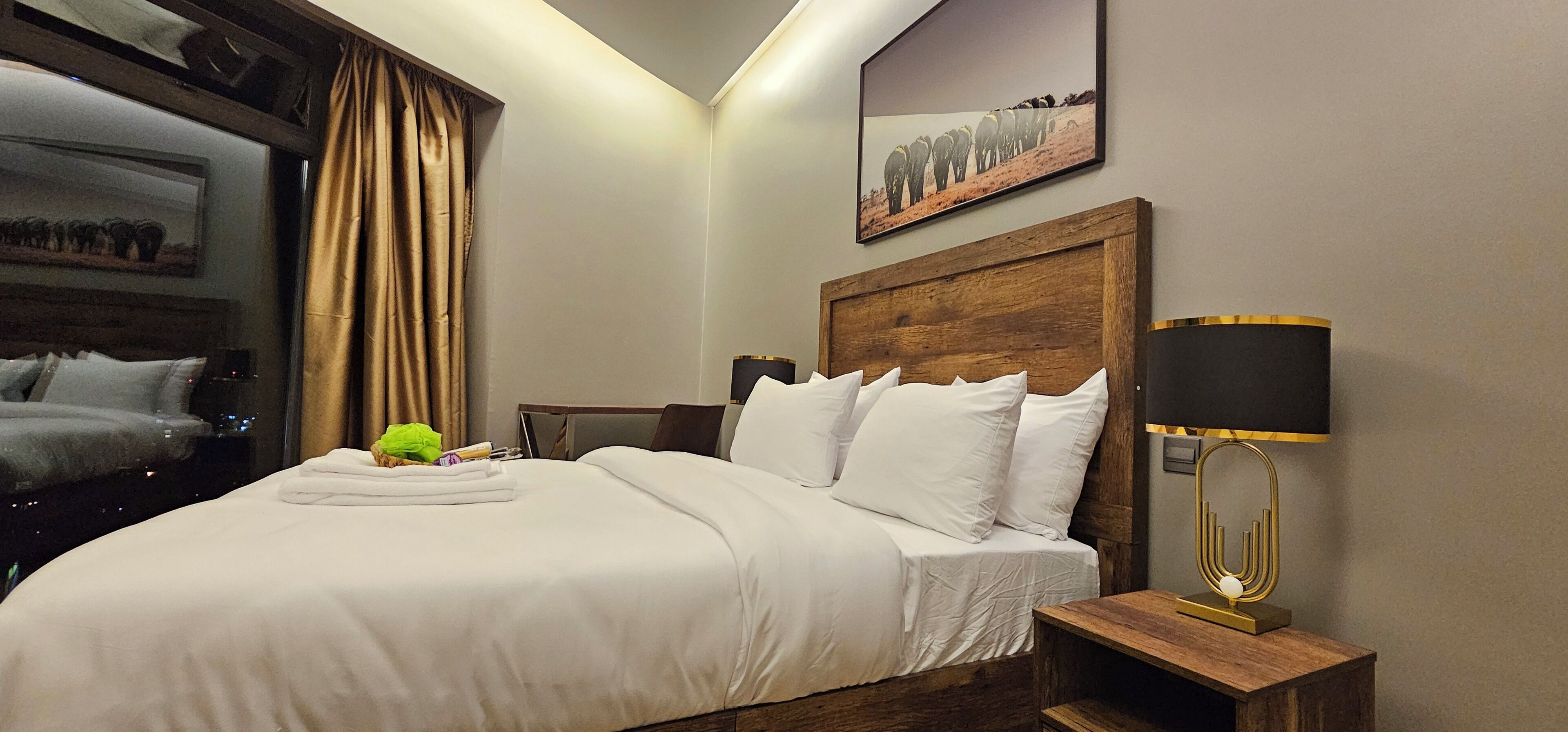 A neatly made bed with white linens, a wooden headboard, and a bedside table with a lamp.