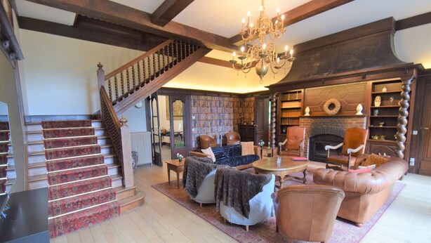 A spacious living room with a staircase, leather furniture, a fireplace, and a large bookcase. - Spa Grand Wellness Villa (Spa)