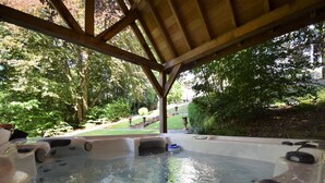 A hot tub area with a wooden pergola overhead, surrounded by lush greenery and a well-maintained lawn. - Spa Grand Wellness Villa (Spa)